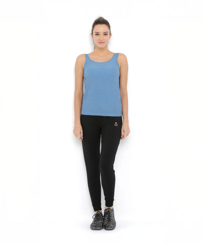 A woman stands against a white background wearing a blue tank top and Black Classic Joggers TLC02, featuring a slim tapered fit, paired with black shoes.