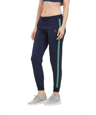 Woman in comfy navy cotton Side Stripe Joggers TLC04SS with green stripes, gray sneakers, and a navy sports bra on a white background.