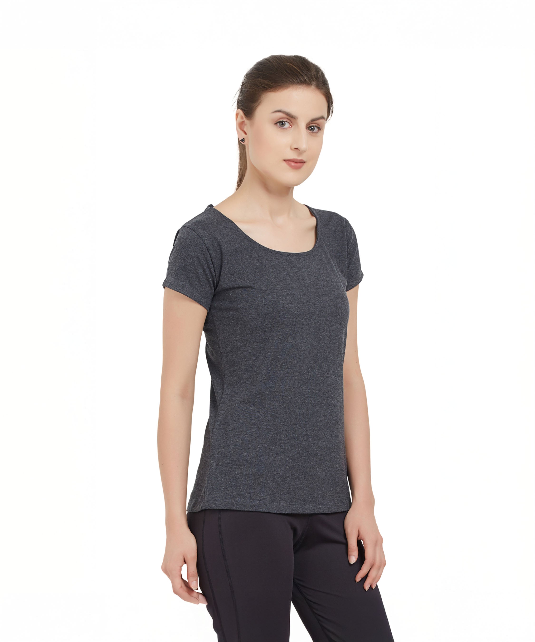 A woman wearing a Grey Round Neck Tee and black pants stands against a plain white background.