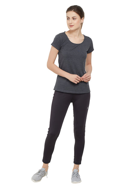 Woman in a Grey Round Neck Tee by TUNA LONDON and black leggings, featuring moisture-wicking fabric, stands looking to the side against a white background.