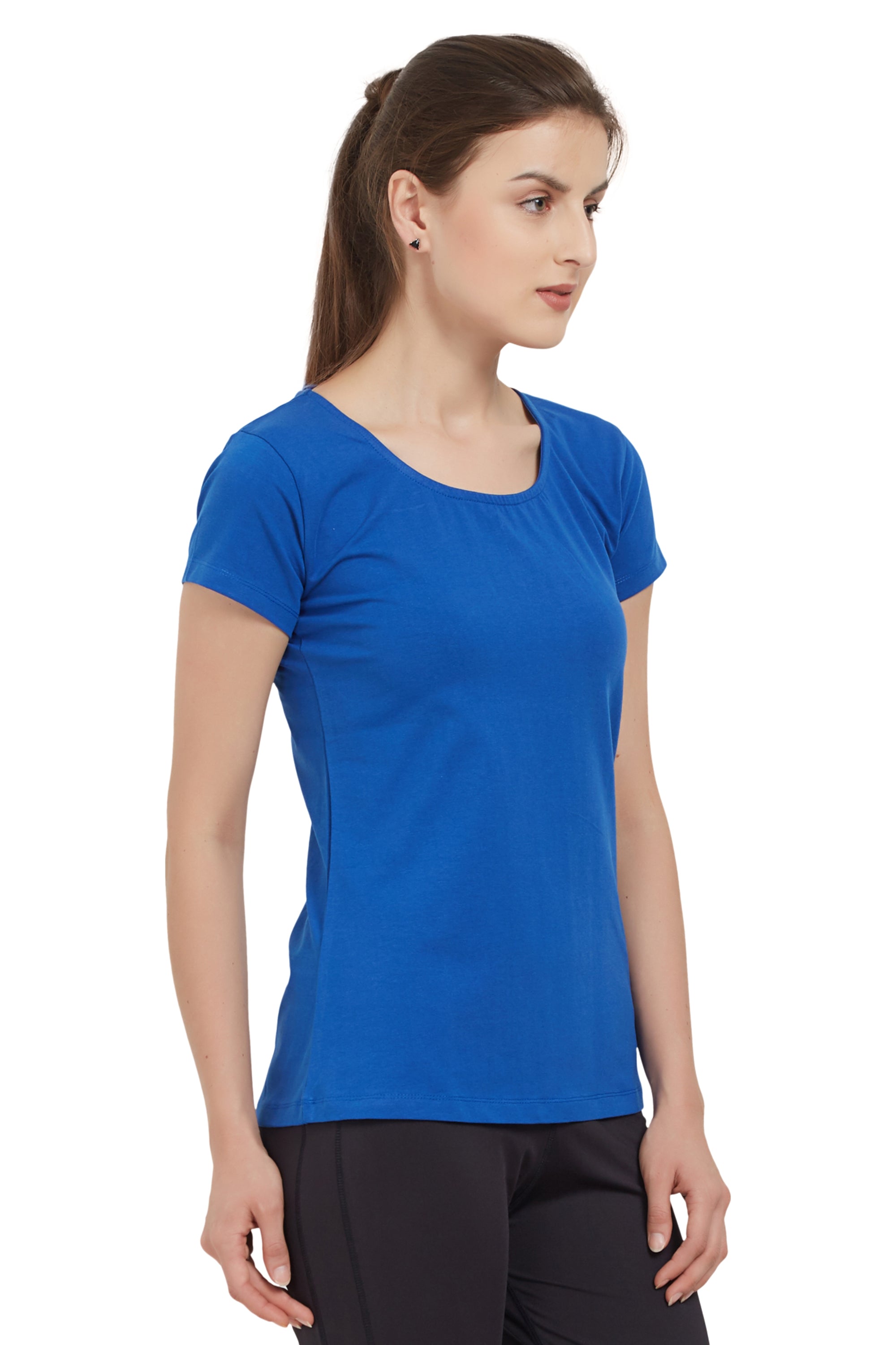 A woman in a Royal Blue Round Neck Tee by TUNA LONDON and black pants stands against a white background, highlighting its moisture-wicking comfort—perfect for active days.