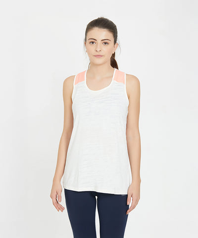 Woman wearing a white sleeveless tank top and navy leggings stands against a plain white background.