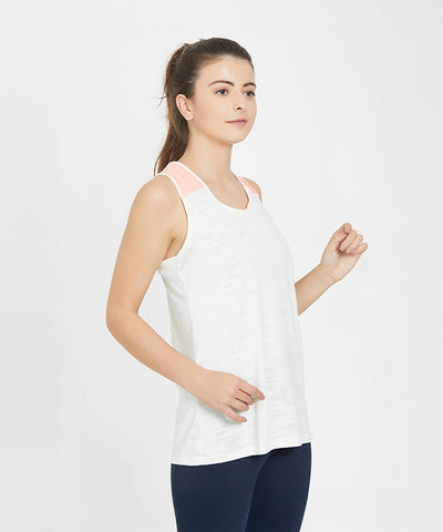 A woman stands against a plain white background, modeling the White Sleeveless Tank Top. She pairs the breathable athletic top with dark leggings, highlighting its simple style.