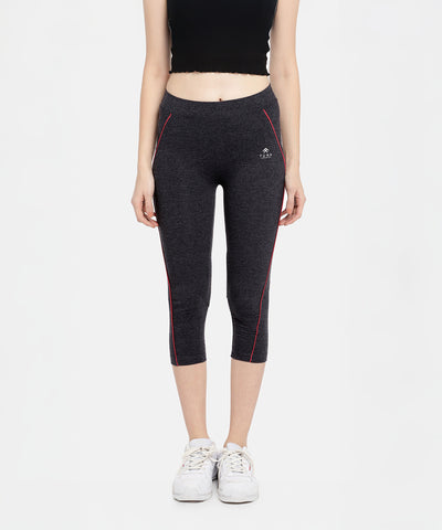 Woman facing forward in a black crop top and Classic Capri TLC67GRY yoga capris, made from heathered fabric with red piping.