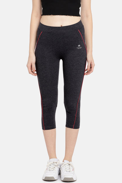 A woman wears the Classic Capri TLC67GRY—dark grey, capri length track pants crafted from soft cotton-spandex with pink piping—paired with white sneakers and a black crop top for stylish, comfortable workouts.