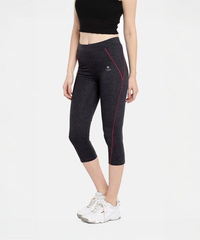 Woman in Classic Capri TLC67GRY, a black crop top, and white sneakers. The capris feature dark grey heathered fabric with red seams.