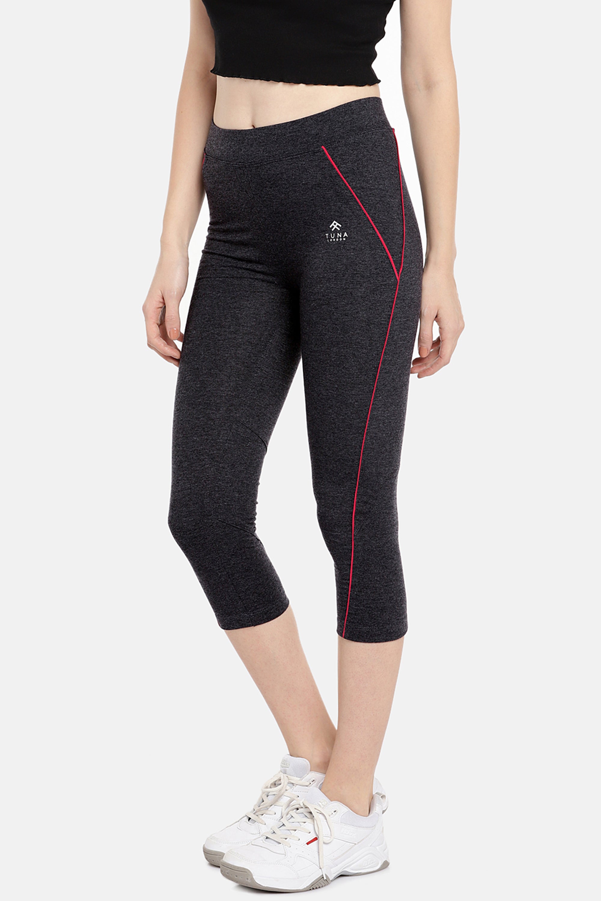 Woman wearing Classic Capri TLC67GRY, black capri-length track pants with pink piping, pairs them with a black crop top and white sneakers. Crafted from comfortable Cotton Spandex Fabrics, perfect for everyday workouts and effortless style.