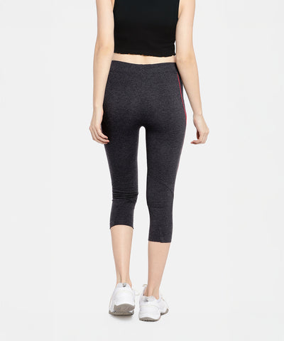 Woman in a black crop top, Classic Capri TLC67GRY yoga capris in heathered fabric, and white sneakers, standing with her back to the camera.
