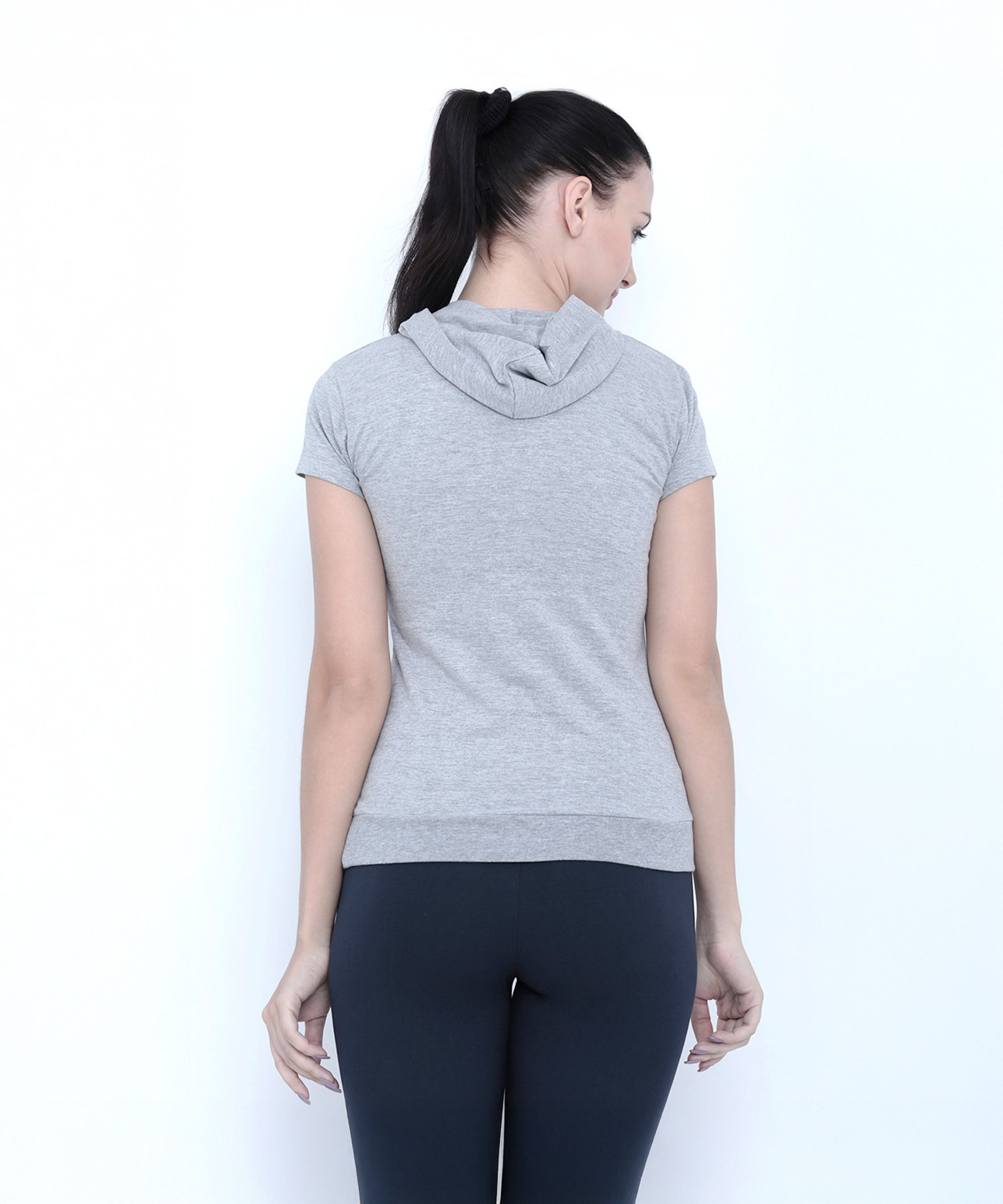 Woman with a ponytail, seen from behind, wears the Grey Hoodie short-sleeve T-shirt and black leggings.