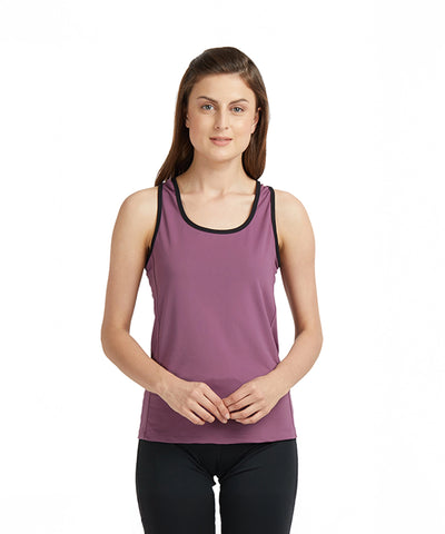 Woman in a Mauve Sleeveless Tee with Back Straps and black leggings stands against a plain white background, highlighting the comfort and style of this moisture-wicking activewear.