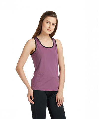 A woman stands against a plain white background, showcasing the moisture-wicking Mauve Sleeveless Tee with Back Straps and black leggings.