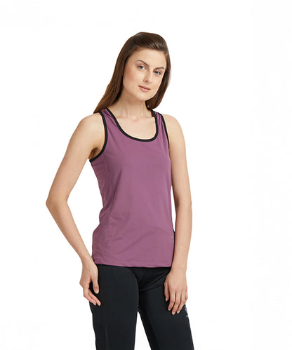 A woman stands against a plain white background, showcasing the moisture-wicking Mauve Sleeveless Tee with Back Straps and black leggings.