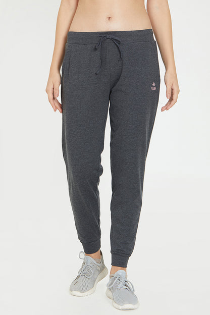 Wearing Classic Joggers 81 in dark gray with an adjustable fit and gray sneakers, standing against a plain light background—ideal for stylish loungewear.