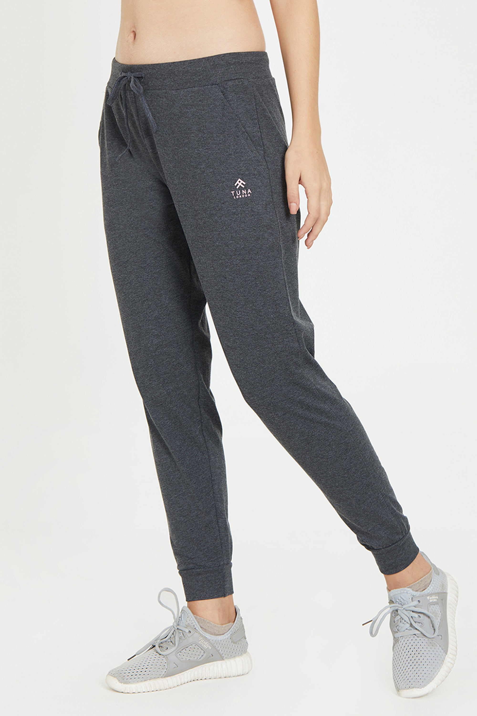 Model showcases Classic Joggers 81—dark jogger pants with an adjustable fit—paired with gray sneakers, pictured from torso to feet against a plain backdrop. Ideal choice for stylish lounge wear.