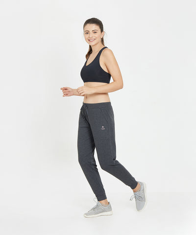 A woman in athletic wear jogs in place, smiling, against a plain white background while showcasing the Classic Joggers 81, designed for comfort and featuring a slim tapered fit.