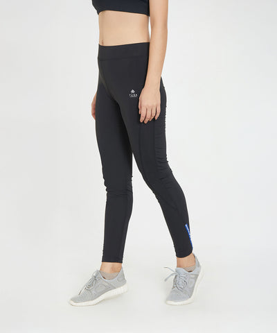 Woman wearing Black Poly Blend Tights for Women - LG10 with a high-rise waistband and a black crop top, paired with grey sneakers and standing against a plain white background—ideal for workout essentials.