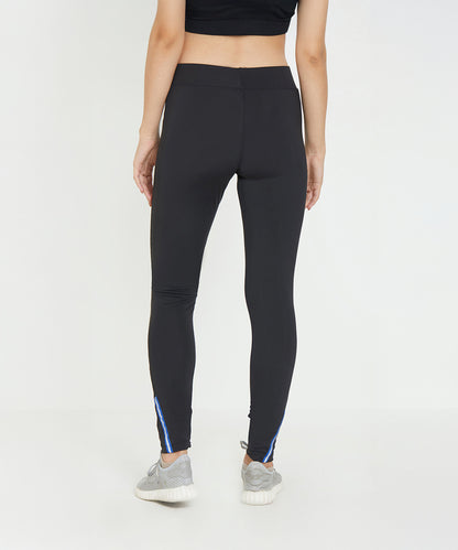 Woman wearing Black Poly Blend Tights for Women - LG10 with a high-rise waistband and sneakers, viewed from the back against a plain white background—ideal workout essentials for any fitness routine.