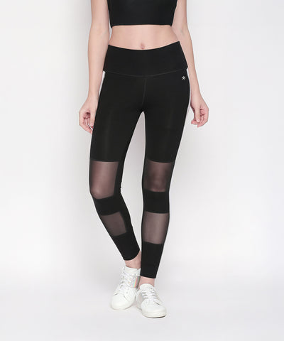 A person wears Black and White High Waisted Leggings - LG13 with a black crop top and white sneakers, standing against a white background.