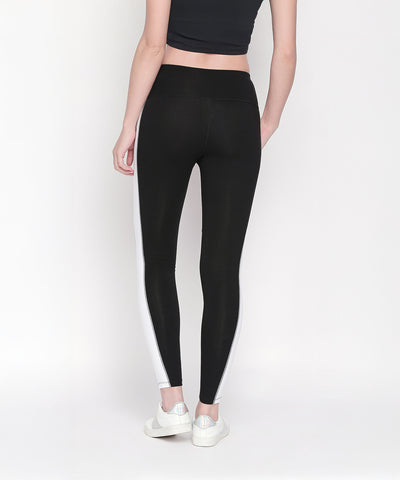 Woman seen from the back in Black and White High Waisted Leggings - LG13 with side stripes, a black crop top, and white sneakers. These high rise leggings are ideal for workouts or casual wear.