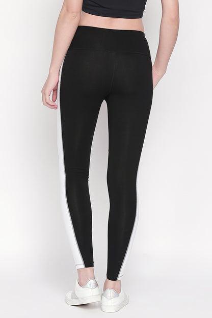 A person is shown from the back wearing Black and White High Waisted Leggings - LG13 with white side stripes and white sneakers.