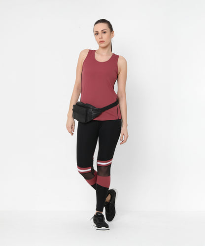 Woman in a maroon tank top, Sienna Black High Waisted Leggings with maroon stripes, black sneakers, and a black waist bag.