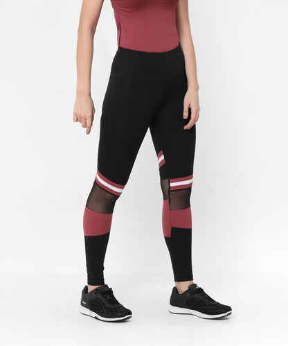A woman wearing Sienna Black High Waisted Leggings with red and white stripes, mesh panels, and black sneakers stands against a white background. The four-way stretch fabric offers comfort and flexibility for any activity.