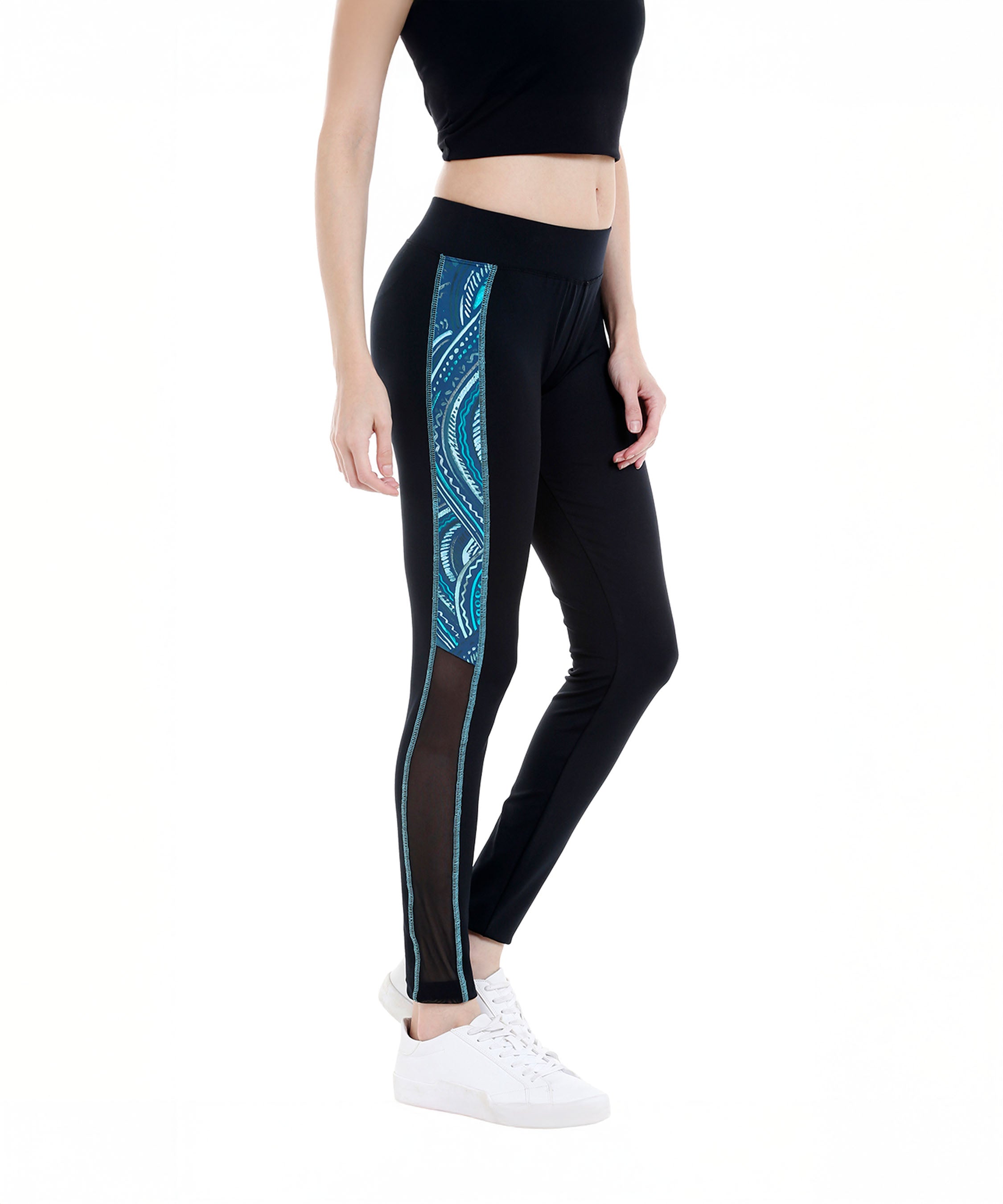A woman wearing Black Sports Leggings G1 with blue patterned side stripes, an elasticated waistband, and comfortable poly blend fabric, styled with a black crop top and white sneakers.