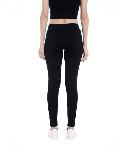 A woman stands facing away on a white background, wearing the Black Sports Leggings G1 with an elasticated waistband, a black top, and white sneakers.