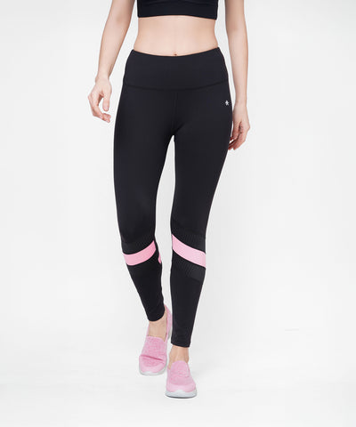 A woman in Black High Waisted Compression Legging With a Neon Pink Patch and pink shoes stands against a white background. The leggings offer four-way stretch compression fabric for comfort.