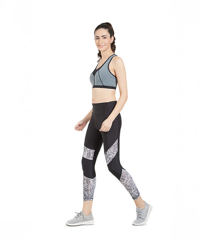 Woman in sportswear walking and smiling, wearing Women Tight Fit Polyester Sports Tights with a high-rise waistband, sports bra, and sneakers on a white background.