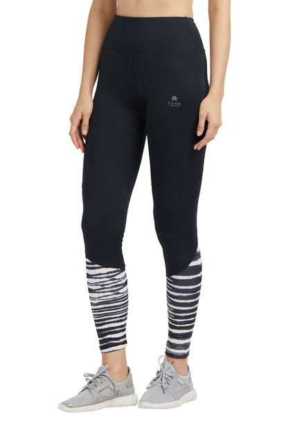 Woman in Black High Waisted Compression Sports Leggings With Zebra Print on the lower legs, paired with light gray sneakers, standing upright.
