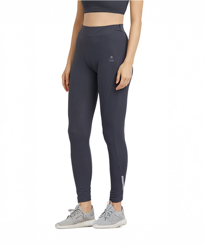A woman stands against a white background wearing Tuna London Grey High Waisted Sports Leggings G9, gray sneakers, and a crop top.