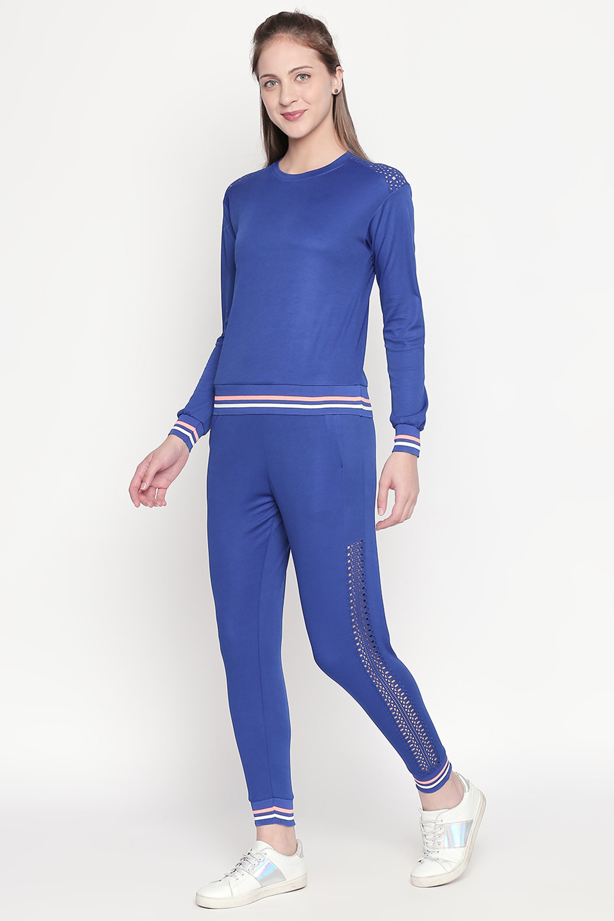 Woman wearing Classic Blue Joggers paired with white sneakers, posing against a plain light background.