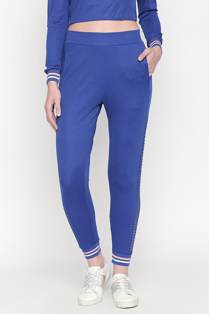 Woman wearing Classic Blue Joggers with striped cuffs and white sneakers, ideal for sports or stylish active wear, standing against a white background.