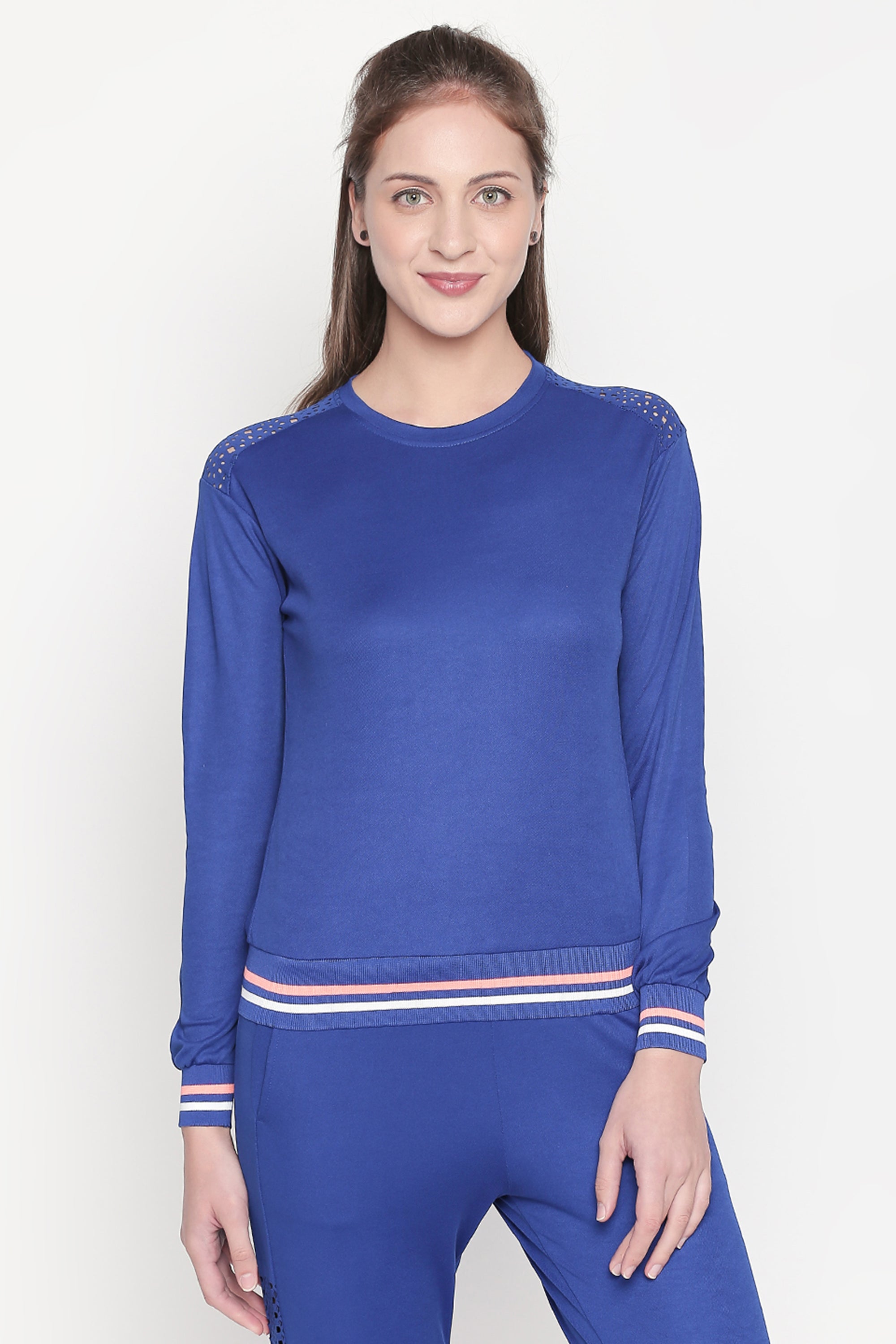 Woman in classic blue joggers with striped cuffs, standing and smiling against a plain light background—ideal for pairing with a tracksuit top for sports activities or casual outings.