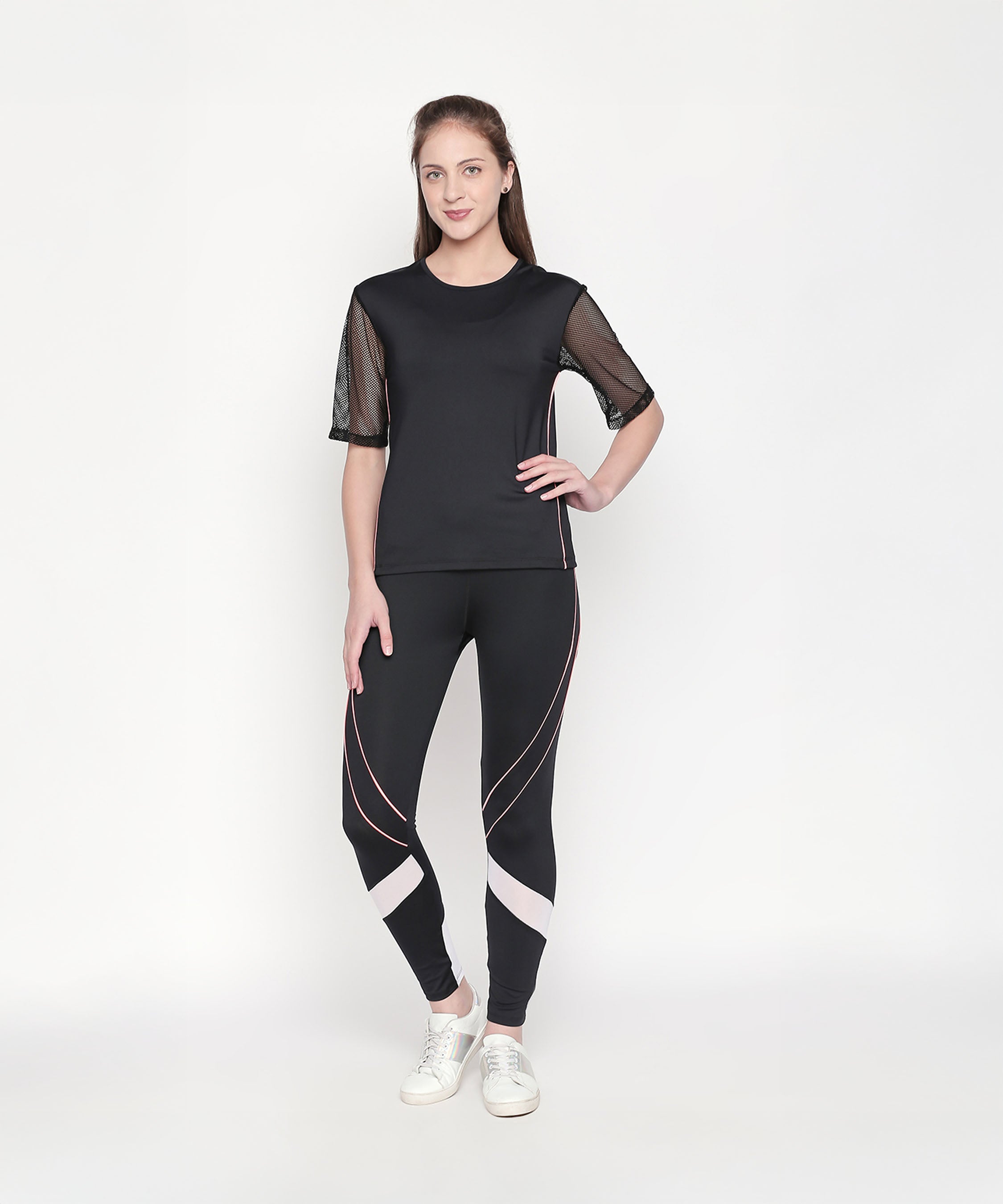 A woman stands and smiles against a plain white background, wearing the Activewear Black Tracksuit featuring mesh sleeves and high-waisted leggings.