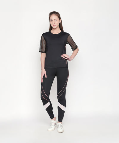 A woman stands and smiles against a plain white background, wearing the Activewear Black Tracksuit featuring mesh sleeves and high-waisted leggings.