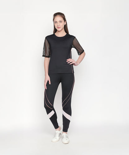 A woman stands and smiles against a plain white background, wearing the Activewear Black Tracksuit featuring mesh sleeves and high-waisted leggings.