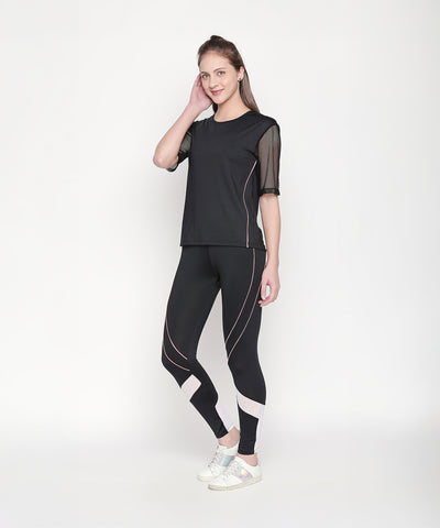 Woman wearing a Black Loose Fit Round Neck Net Half Sleeve Top, featuring moisture-wicking mesh, posing and smiling against a plain white background.