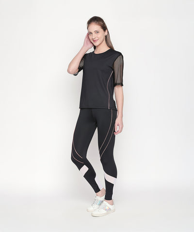 A woman poses confidently against a white background in the Activewear Black Tracksuit, featuring high waisted, moisture-wicking leggings and white sneakers.