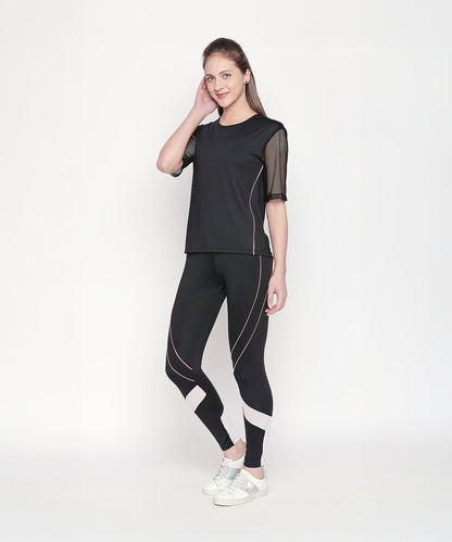 A woman poses confidently against a white background in the Activewear Black Tracksuit, featuring high waisted, moisture-wicking leggings and white sneakers.