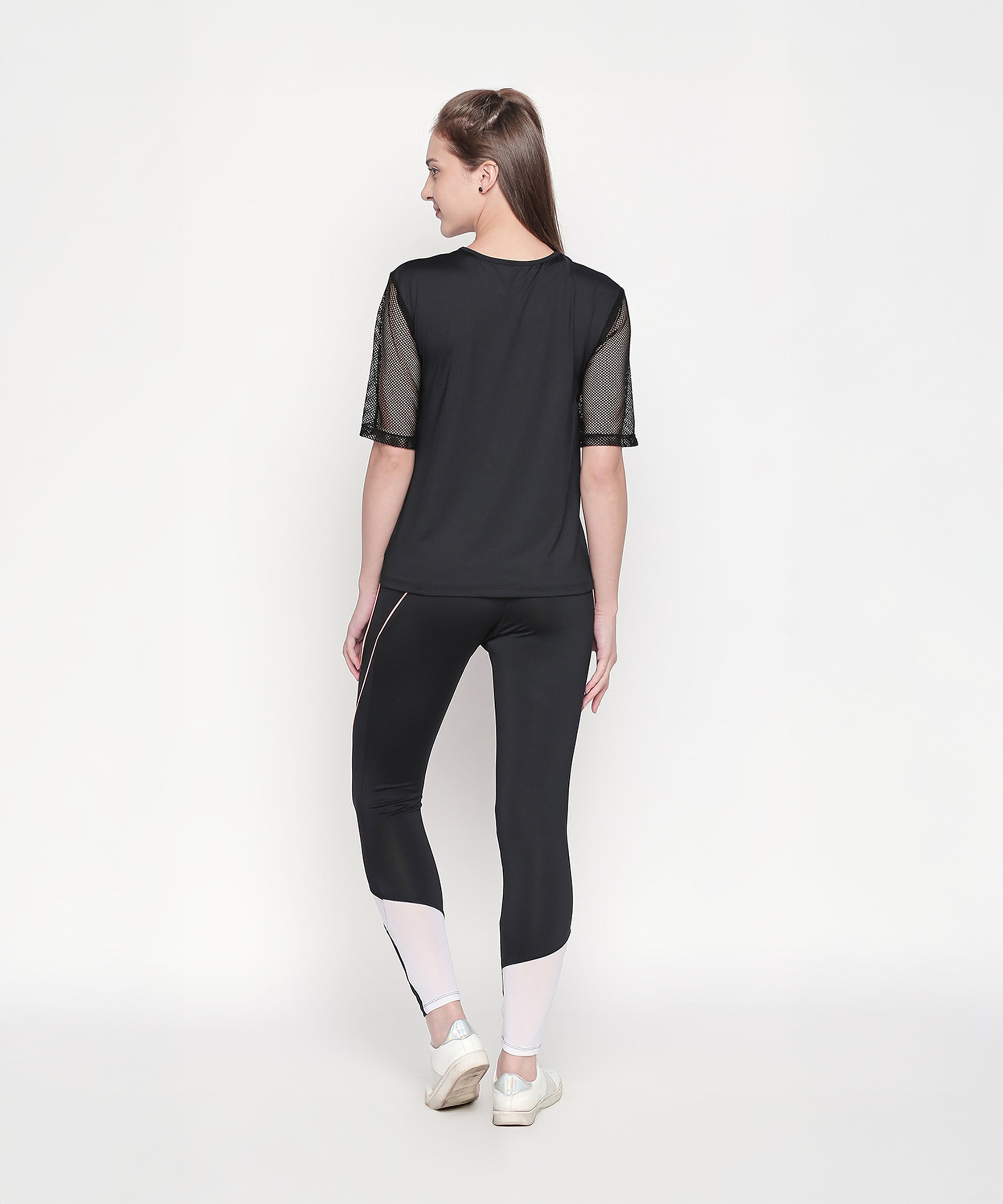 Woman wearing the Activewear Black Tracksuit with high-waisted leggings and white sneakers stands against a plain white background, facing away.
