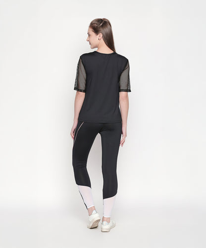 Woman wearing the Activewear Black Tracksuit with high-waisted leggings and white sneakers stands against a plain white background, facing away.