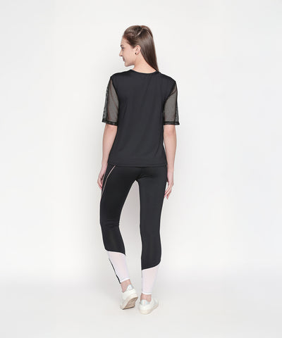 Woman wearing a Black Loose Fit Round Neck Net Half Sleeve Top, moisture-wicking and stylish, facing away on a white background.