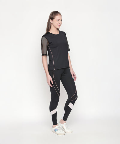 Woman wearing the Activewear Black Tracksuit with high-waisted leggings and mesh sleeves, paired with white sneakers, stands against a plain white background.