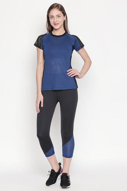 Woman in a Sportswear Dark Blue Tracksuit stands smiling against a plain light background, ready to elevate her workout experience.