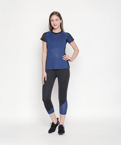 Woman in athletic wear poses against a plain white background, wearing the Blue - Textured Top With Net Sleeves and black leggings.