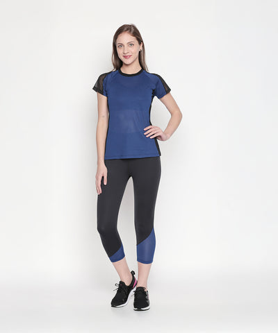 Woman wearing Black High Waisted Leggings 74 and a blue athletic top poses against a plain white background.