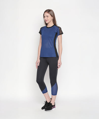 Woman wearing the Blue - Textured Top With Net Sleeves and black athletic pants, featuring a regular fit and moisture-wicking fabric, standing against a plain white background.
