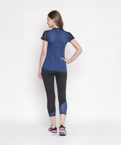 A woman wearing Black High Waisted Leggings 74 and a blue sports top stands with her back to the camera against a white background.